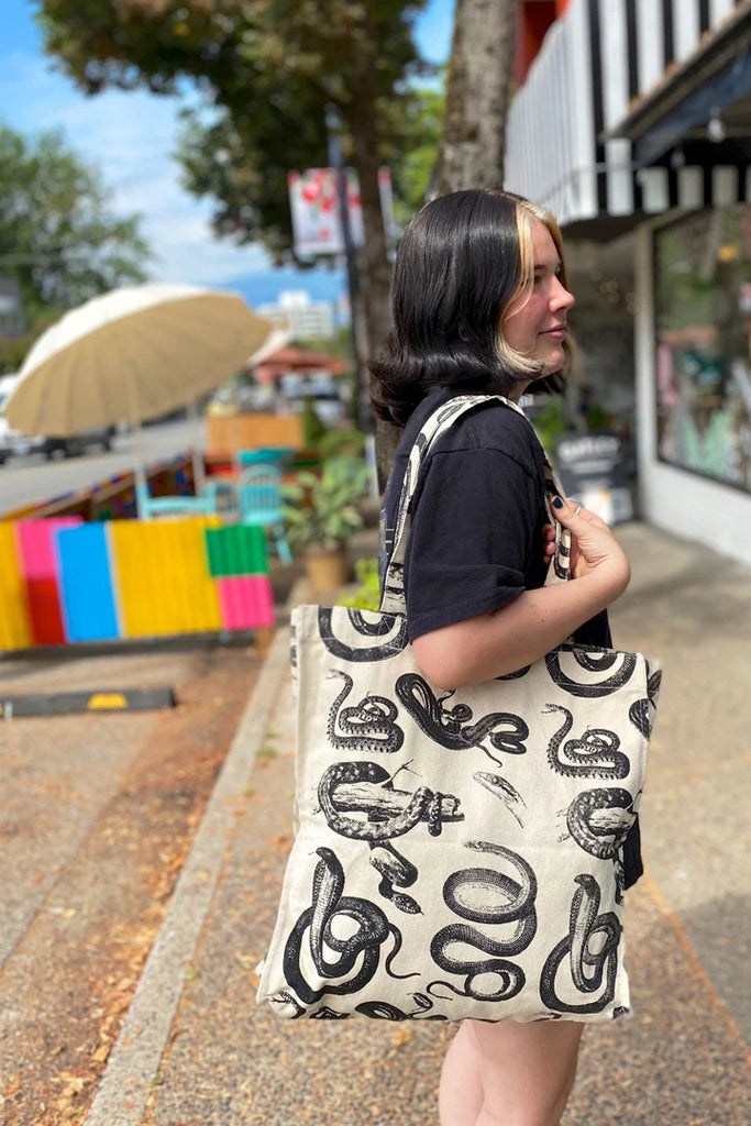 a girl carrying a tote bag, design on the bag is many different snakes